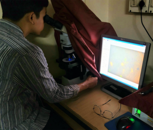 Kaushik Dowarah observing microplastics under a microscope in Pondicherry University.